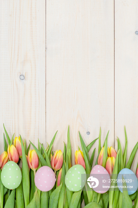 Tulips  and easter eggs over wooden background. Backdrop with empty space for text