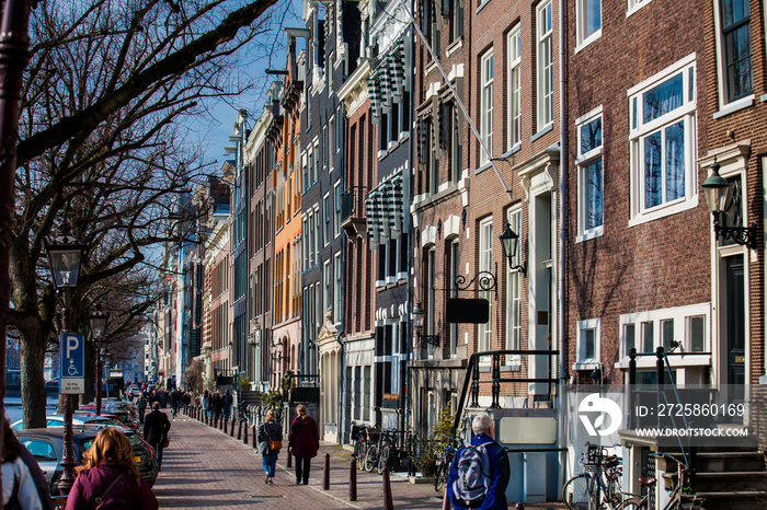 People walking and riding bicycles at the beautiful cobblestone streets next to the canals of the Ol