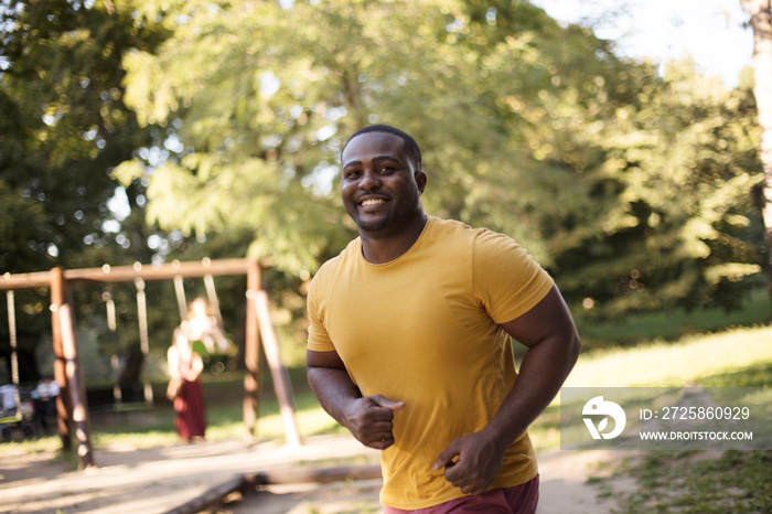 Day is beautiful for running.  African American man running trough park.