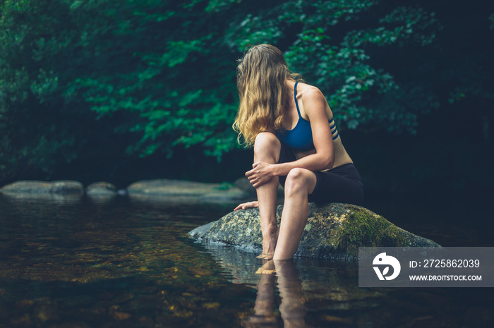 Woman relaxing on rock in river