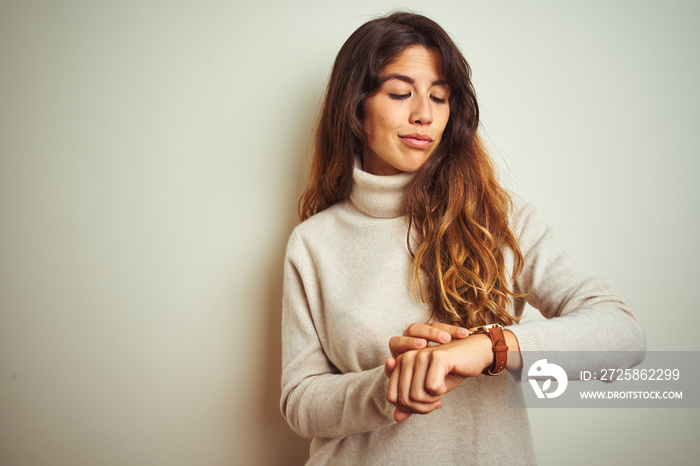 Young beautiful woman wearing winter sweater standing over white isolated background Checking the ti