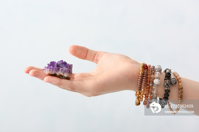 Female hand with beautiful amethyst on light background