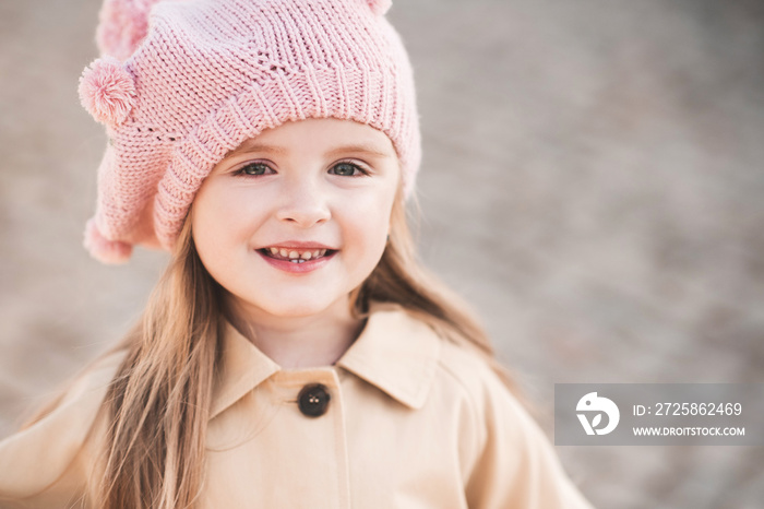 Smiling baby girl 2-3 year old wearing knitted hat and jacket outdoors close up. Childhood. Autumn s