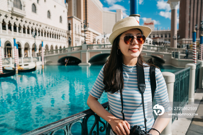 smiling asian japanese lady traveler holding camera standing outdoors with venetian bridge and beaut