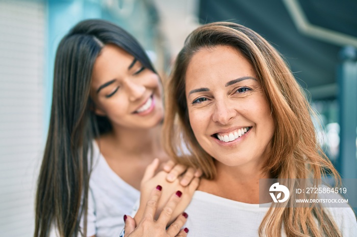 Beautiful hispanic mother and daughter smiling happy standing at the city.