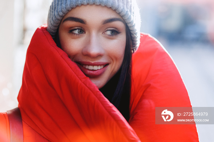 Close up portrait of pretty fashion woman in red coat and grey hat. Girl smile and look away. Beauty