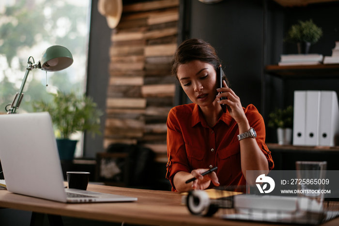 Businesswoman using phone. Happy young woman talking to the phone in office.