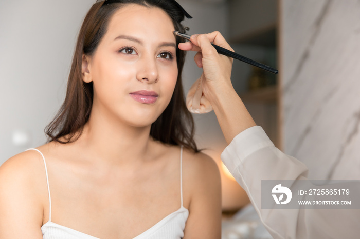 Young asian woman in bedroom. Make-up artist in beauty studio doing makeup for beautiful girl.Beauti