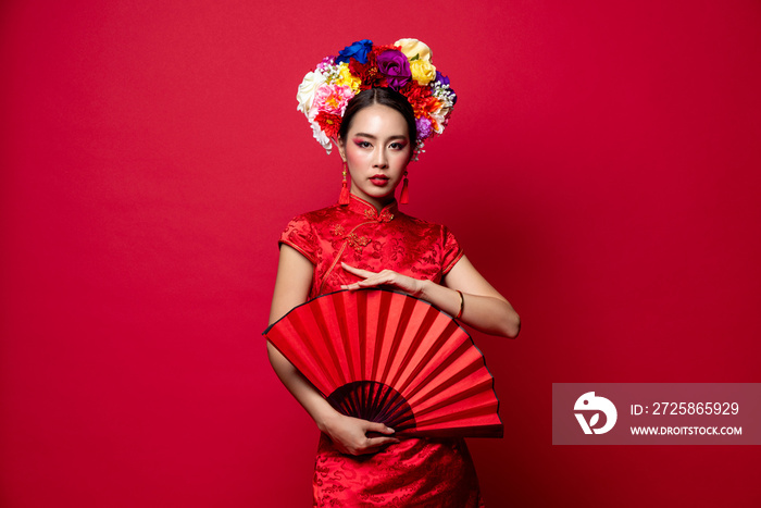 Beautiful elegant Asian woman wearing traditional dress with flower chaplet holding red fan in isola