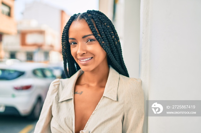 Young african american woman smiling happy leaning on the wall at the city.