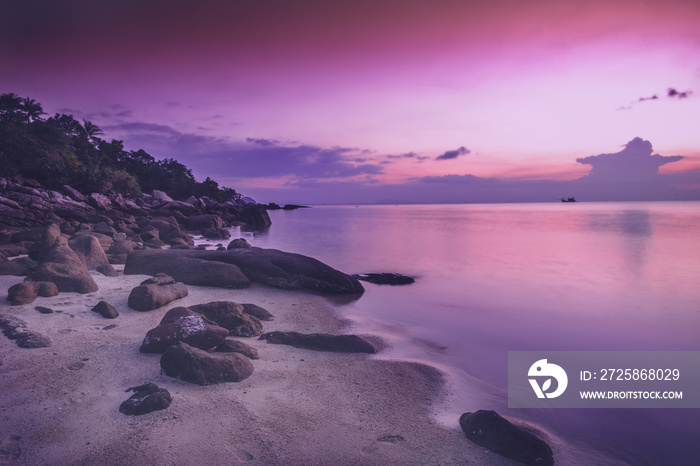 海边美丽的亮紫粉色日落，沙滩上的石头。令人惊叹的景色
