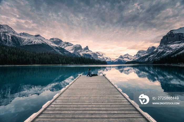 Traveler relaxing on wooden pier in Maligne lake at Spirit island, Jasper national park