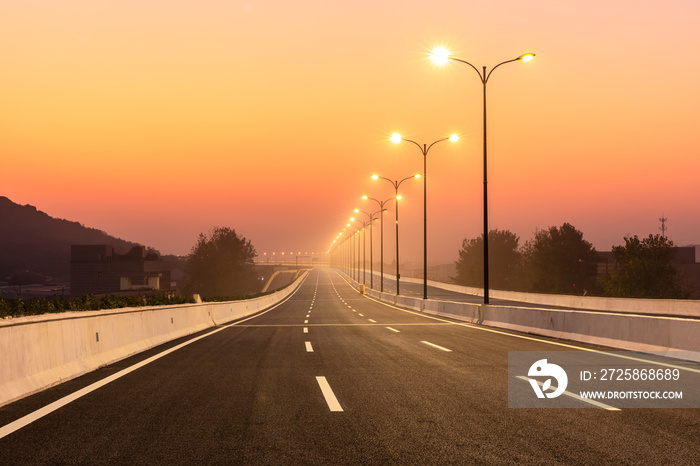 City road and bright street lights landscape at sunset