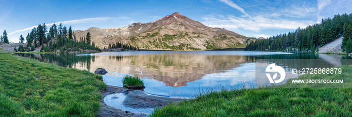 Volcanic mountain in morning light reflected in calm waters of lake.	