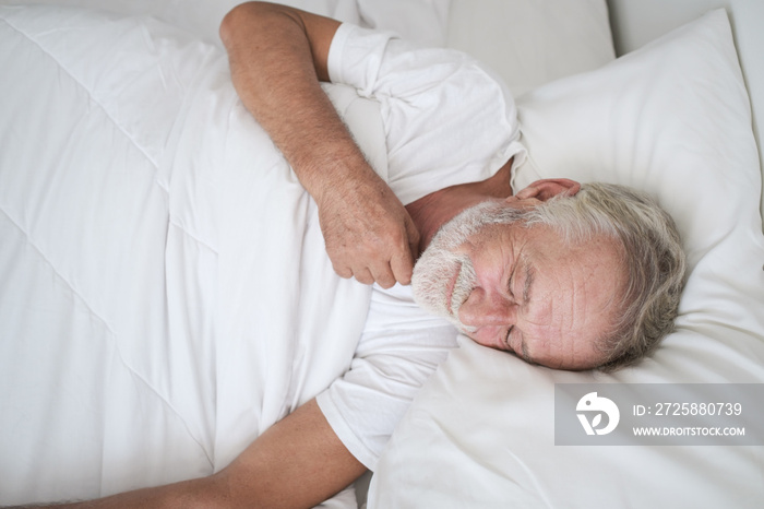 senior man sleeping alone and headache or dreaming nightmare on bed in room