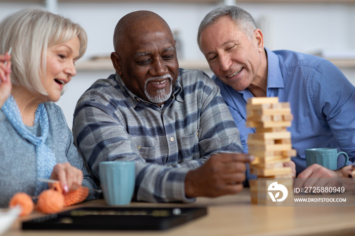 Closeup of multiracial senior people playing jenga at home