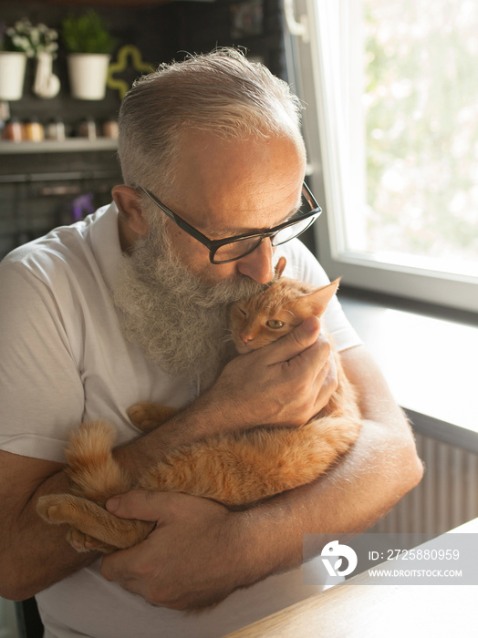 一位老人带着他的猫在笔记本电脑上工作，微笑着看着屏幕。