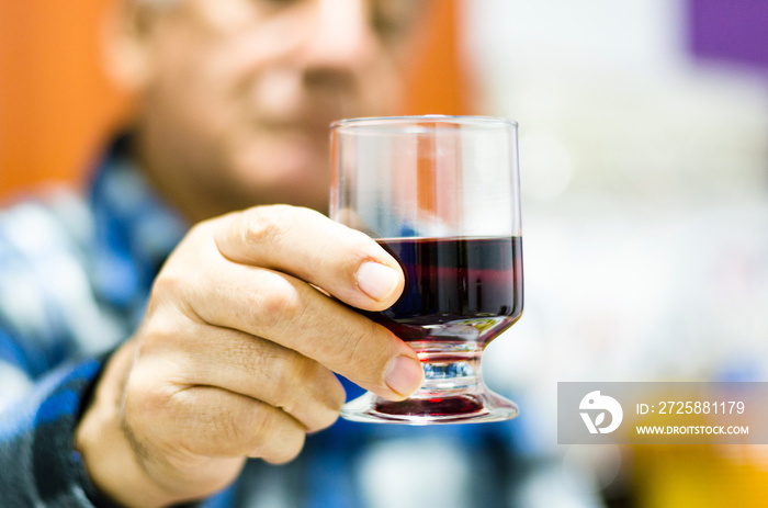 middle age man holding and looking in a glass of wine.
