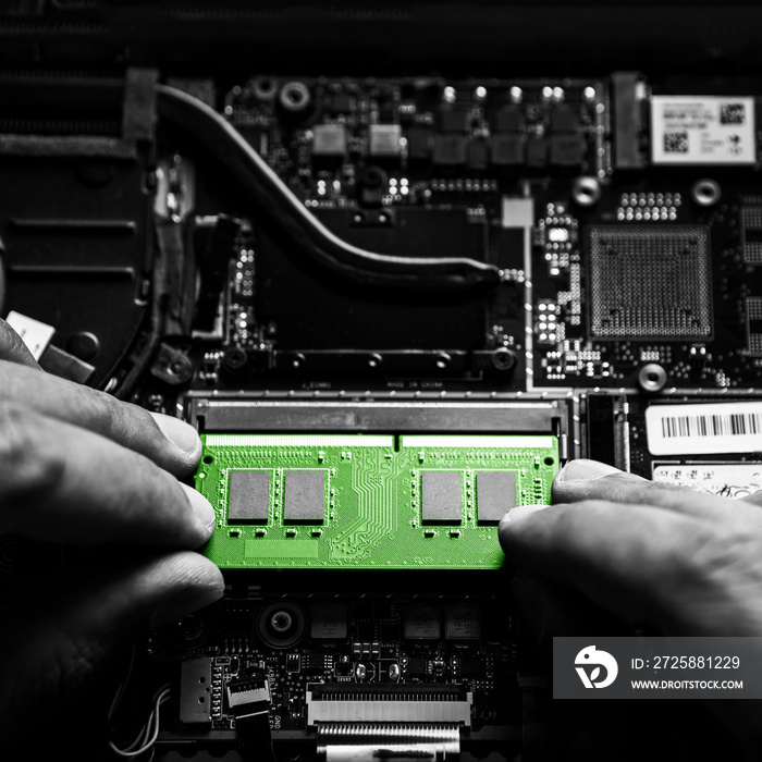 Close-up on the green RAM memory that the hands of the service technician insert into the slot on th