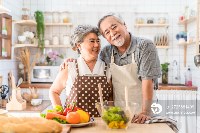 Couple senior Asian elder happy living in home kitchen. Grandfather cooking salad dish with grandmot