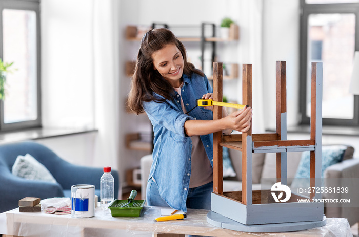 修理、diy和家居装修理念——幸福微笑的女人拿着尺子量着旧木桌