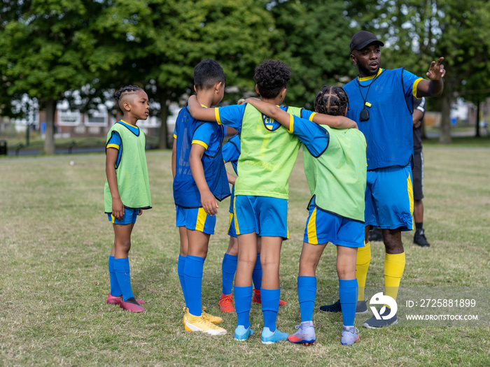 Coach giving instructions to kids (8-9) on soccer field