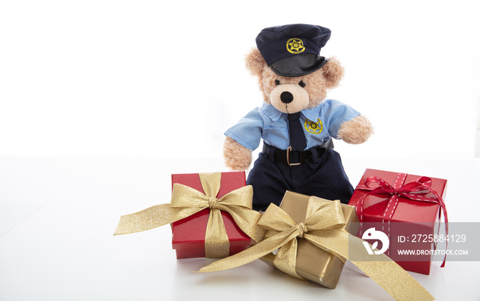 Cute teddy in policeman uniform and christmas presents isolated against white background
