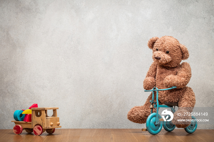 泰迪熊坐在老式复古玩具三轮车和过时的经典木卡车上，带着建筑包