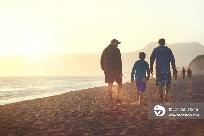 Boy (8-9) with father and grandfather walking on beach