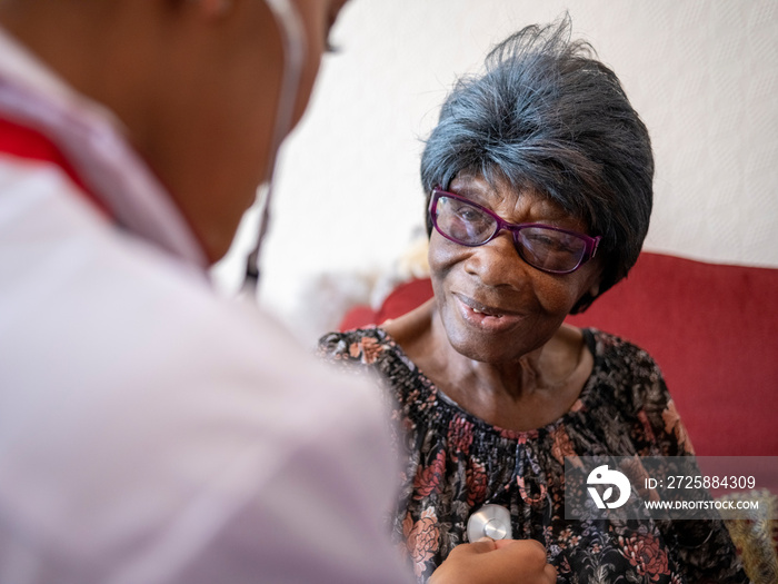 Nurse�taking care of elderly woman, examining chest with stethoscope