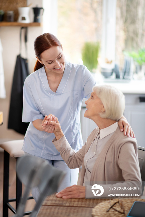 Smiling caregiver supporting pensioner after surgery