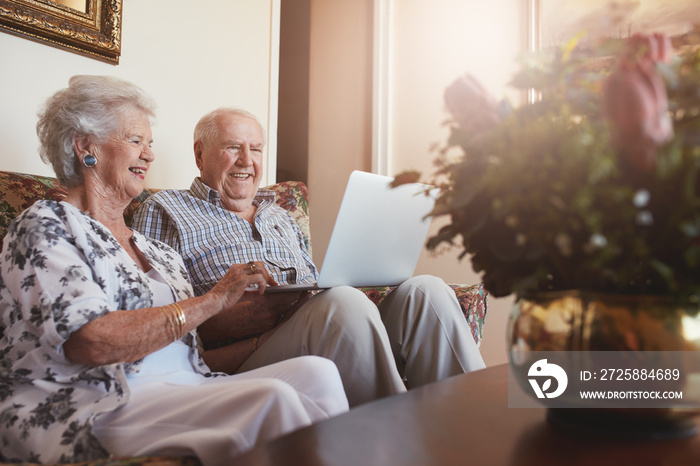 微笑的老年夫妇在家使用笔记本电脑