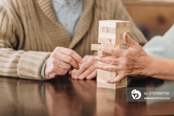 cropped view of senior couple playing jenga at home