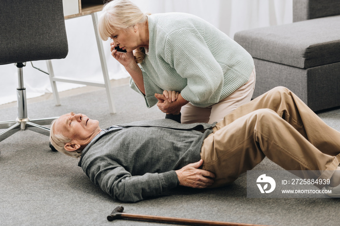 senior woman looking at husband who falled down with heart attack and dying