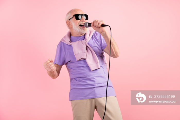 Photo portrait of funky senior man singing on stage keeping microphone wearing sunglass isolated on 