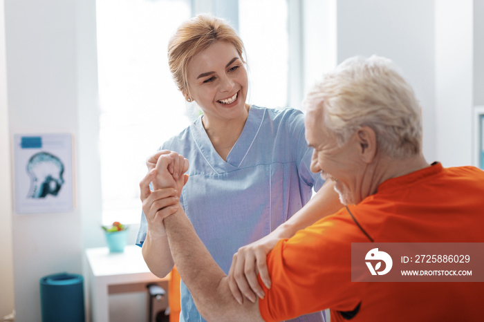 Joyful positive nurse smiling to her patient