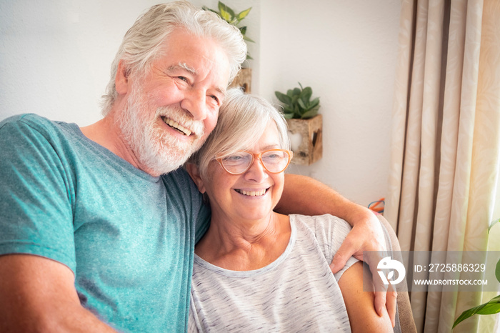 An attractive elderly couple relax on the colorful armchair by embracing each other. Positive moment