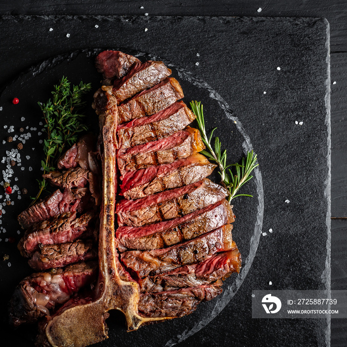 Dry Aged Barbecue Porterhouse Steak T-bone beef steak sliced with large fillet piece with herbs and 