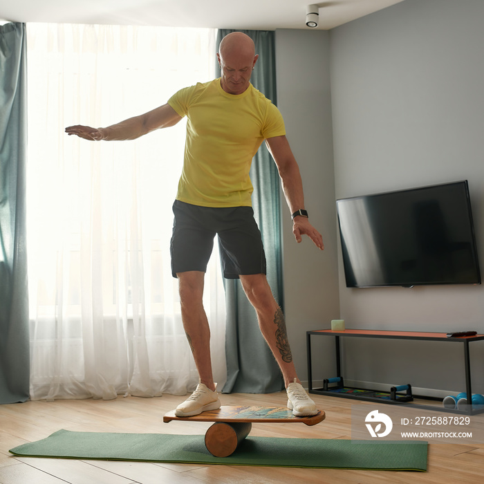 Muscular middle aged man standing on balance board