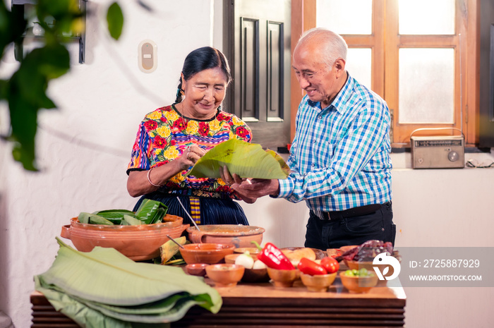 Pareja de adultos mayores haciendo tamales. Abuelos cocinando juntos se divierten.