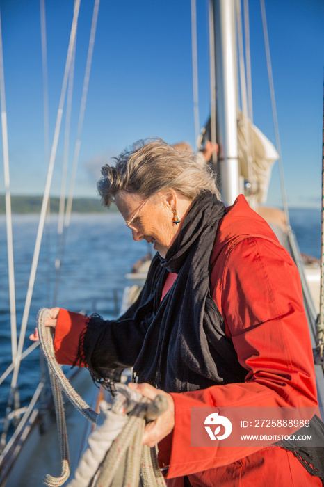 Senior woman on sailboat holding ropes