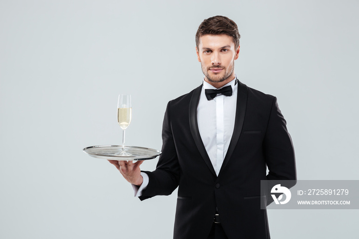 Butler in tuxedo holding tray with glass of champagne