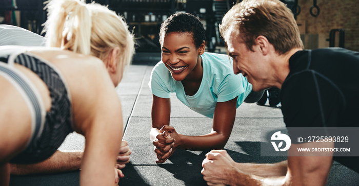 Smiling friends planking together during a gym workout class