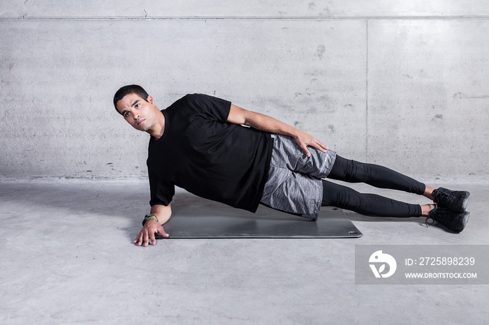 Focused sportsman in side plank looking forward