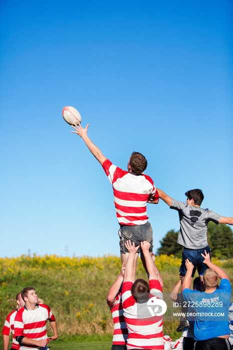 Rugby player jumping to catch ball in line out supported by teammates