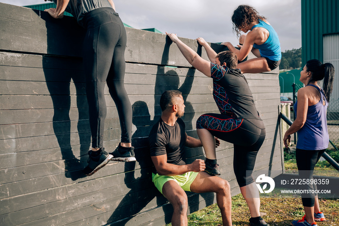 Group of participants in an obstacle course climbing a wall