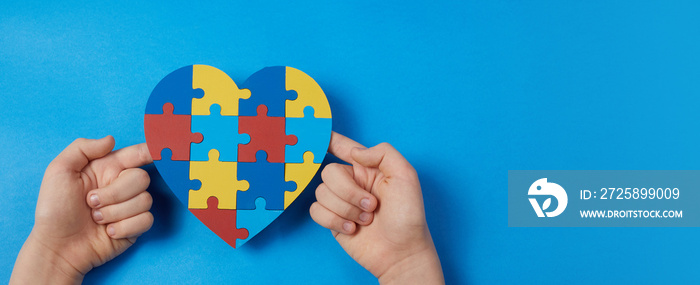 Autistic boy hands holding jigsaw puzzle heart shape. Autism spectrum disorder family support concep