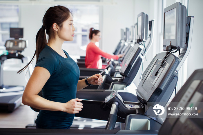 Side view of woman exercising on treadmill in gym