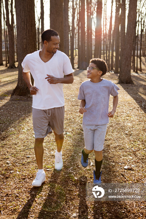 Father and son (10-11) jogging in woods