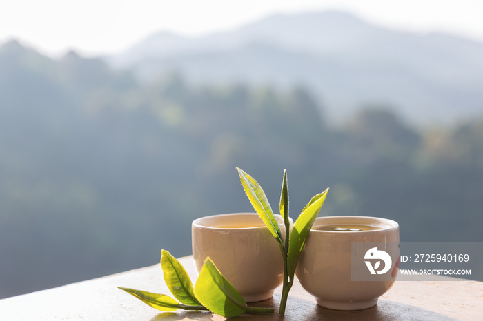 两杯茶叶放在桌子上，俯瞰着阳光明媚的山脉景观。美丽的自然背景。